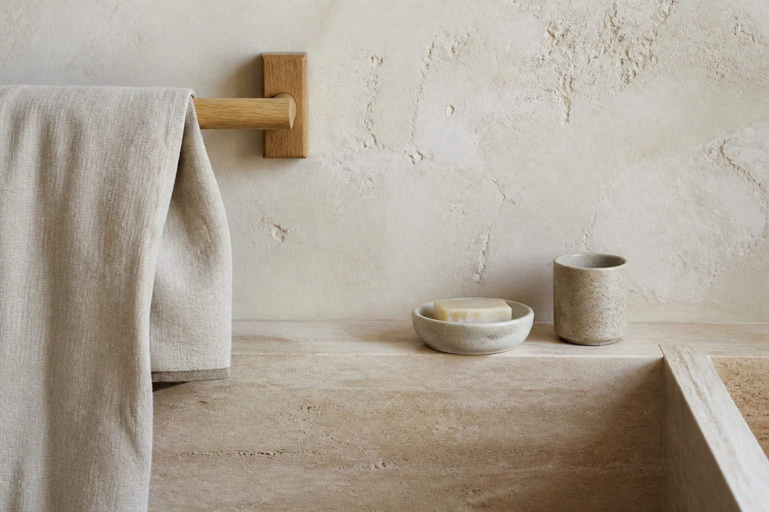 Linen and ceramic accessories on a limestone bathroom shelf